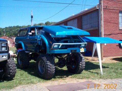 1978 Ford Bronco - A modified 1978 Ford Bronco is displayed with its hood up, parked on grass next to another vehicle.