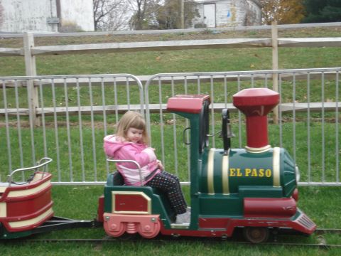 2000 Ford Crown Victoria - A young girl sits in a toy train at an outdoor event.
