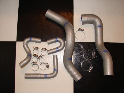 1992 Ford Taurus - A set of silver radiator hoses with blue markings and metal hose clamps are displayed on a black and white checkered surface.