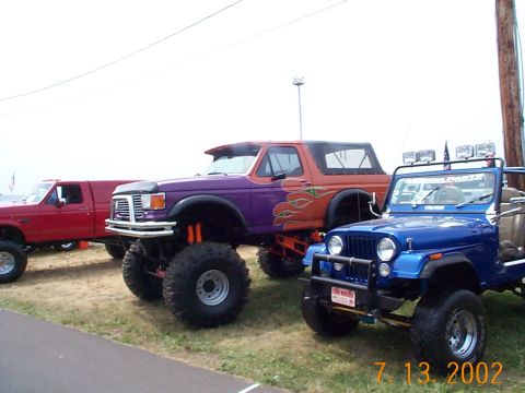 1978 Ford Bronco - A lifted 1978 Ford Bronco with custom paint and flame decals is parked next to a blue Jeep.