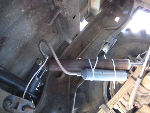 1989 Ford Bronco - Close-up of an aftermarket steering stabilizer installation on a vehicle's frame.