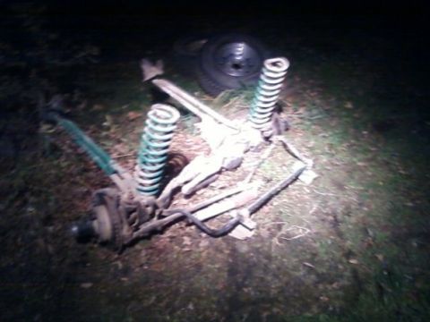1994 Ford Bronco - Vehicle suspension components lie scattered on the ground, illuminated by a spotlight.