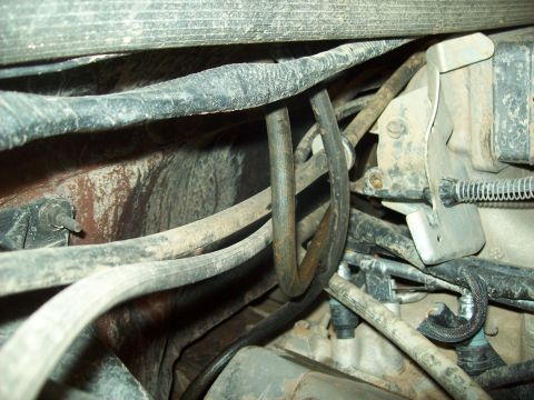 1985 Ford Bronco - Tangled wiring and hoses are visible in the engine bay of a vehicle.