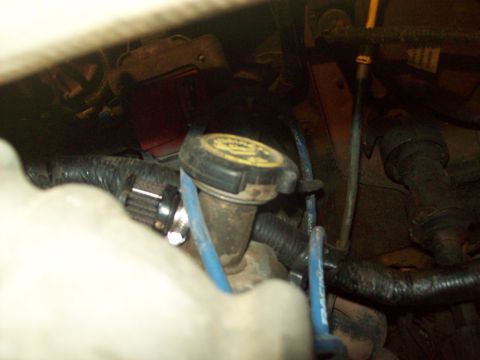 1985 Ford Bronco - A close-up view of engine bay components, including a coolant reservoir cap and various hoses.