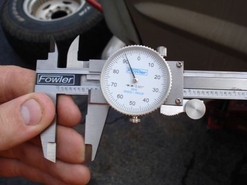 1967 Ford F-250 - Using a Fowler dial caliper to measure a component. Background shows a tire and vehicle exterior.