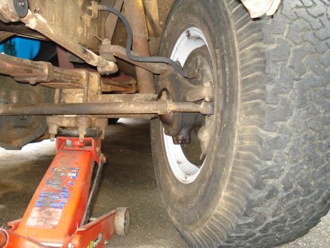 1967 Ford F-250 - Close-up view of a vehicle's front wheel and suspension system, supported by a jack.