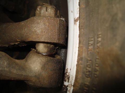 1967 Ford F-250 - Detail of a vehicle's rusty steering linkage and a tire sidewall with load information visible.