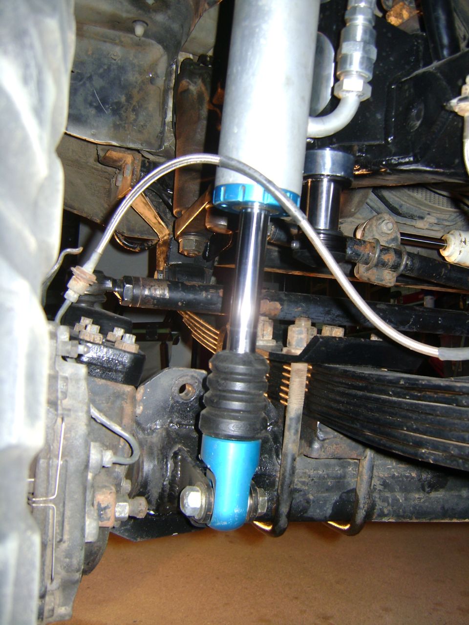 Front suspension shock absorber with blue base, attached to leaf springs and steering components