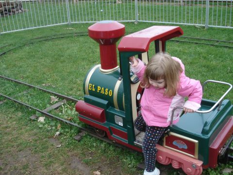 2000 Ford Crown Victoria - A young child in a pink jacket climbs onto a miniature train with 'El Paso' written on its side.