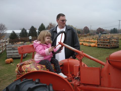 2000 Ford Crown Victoria - A young girl pretends to drive a tractor at a pumpkin patch with a man watching.