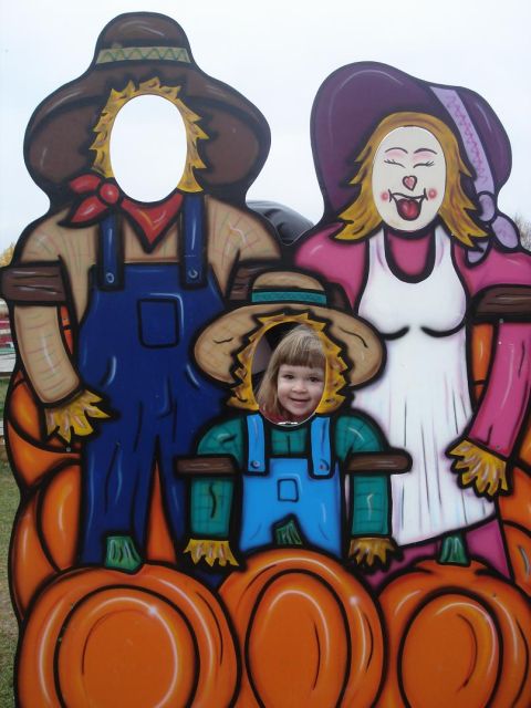 2000 Ford Crown Victoria - A child poses for a photo in a scarecrow family cutout at a fall festival.