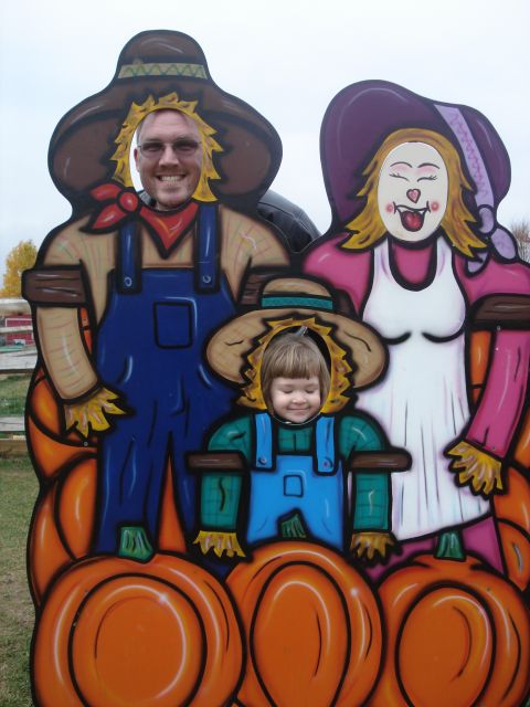2000 Ford Crown Victoria - A family poses for a photo in a cutout designed to look like scarecrows at a fall festival.