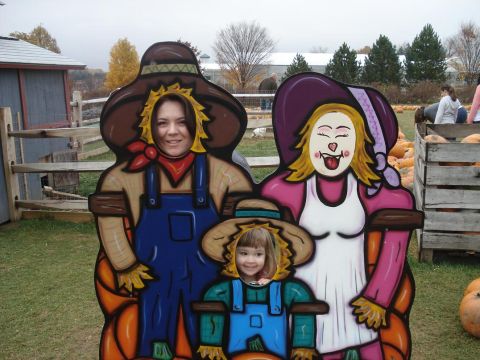 2000 Ford Crown Victoria - People pose for a photo in a scarecrow-themed cutout at an outdoor fall event.
