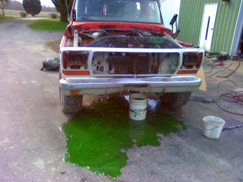 1979 Ford F-100 - A red 1979 Ford F-100 truck sits with its hood open and a large puddle of green coolant on the ground.