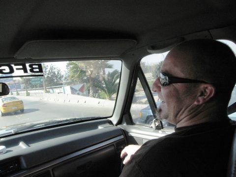 1986 Ford Bronco - View from inside a vehicle, showing the driver and the road ahead with another car.