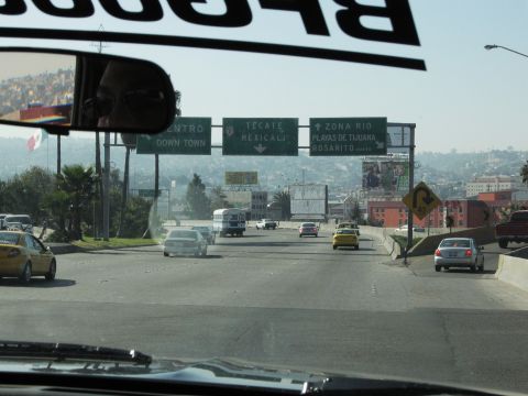 1986 Ford Bronco - Driving on a highway with multiple vehicles and city skyline in the background. Signs indicate directions to various locations.