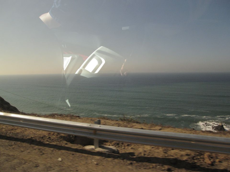 reflection of car interior and dashboard on window overlooking the ocean