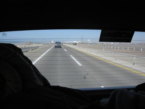 1986 Ford Bronco - View from inside a vehicle looking out at a silver SUV on a highway with the ocean in the distance.