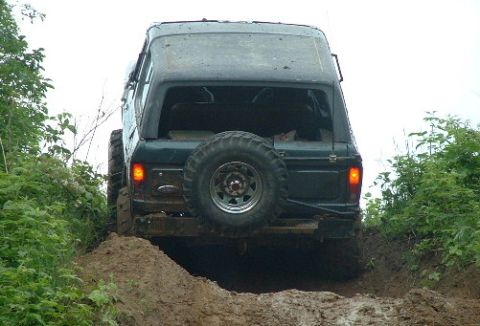 2002 Ford F-350 - Off-road vehicle navigates a challenging dirt track, showing its rear profile and spare tire.