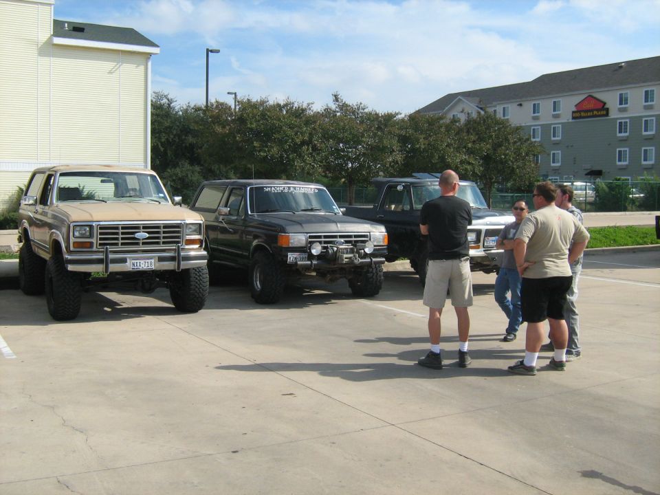 Tan 1980 Ford Bronco with lifted suspension and large tires parked in a lot