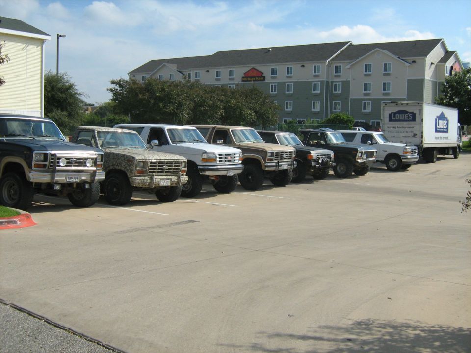 Several Ford Broncos and F-Series trucks parked in a lot, with a Lowe's truck in the background
