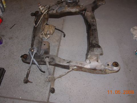 1991 Ford Taurus - A disassembled front subframe assembly, including the steering rack, is shown on a garage floor.