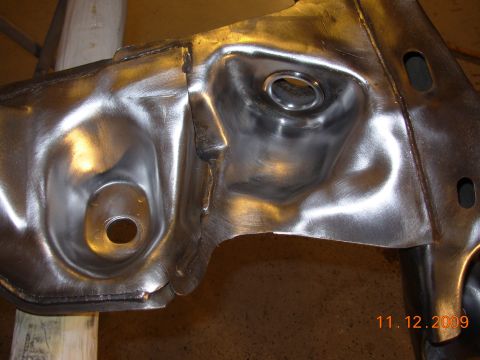 1991 Ford Taurus - A close-up view of a bare metal automotive component, possibly a subframe or suspension part, with visible stamping and welding marks.