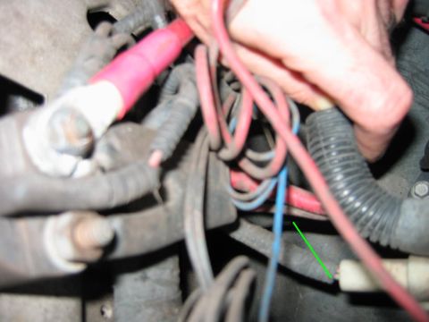 1992 Ford Bronco - Close-up view of automotive battery cables, with a hand manipulating a connection point.