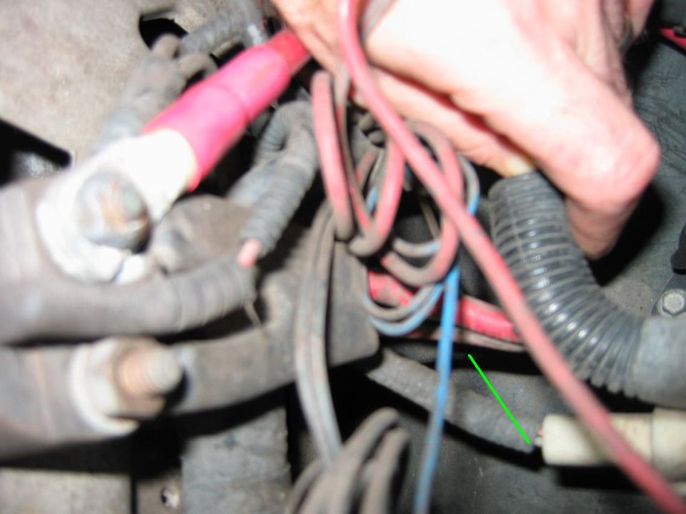 Close-up of red and blue battery cables with a hand adjusting a connection