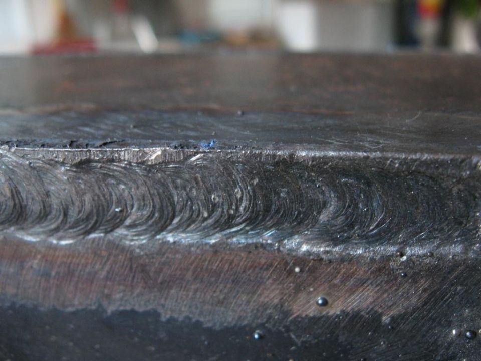 Close-up of a metal seam with visible weld beads and some small bubbles