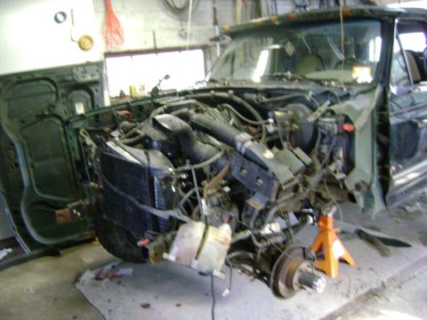 1994 Ford Bronco - The front end of an SUV is disassembled, revealing the engine bay and radiator, indicating a repair or rebuild process.