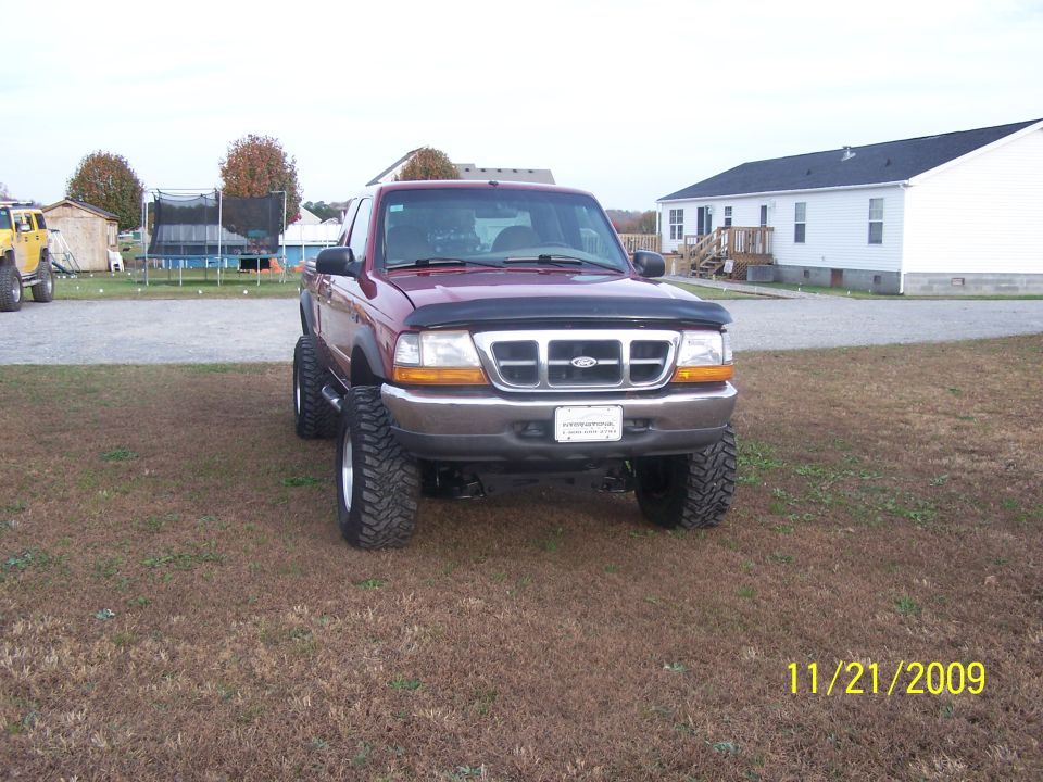 Lifted dark red Ford Ranger extended cab, front view, mud tires and hood deflector