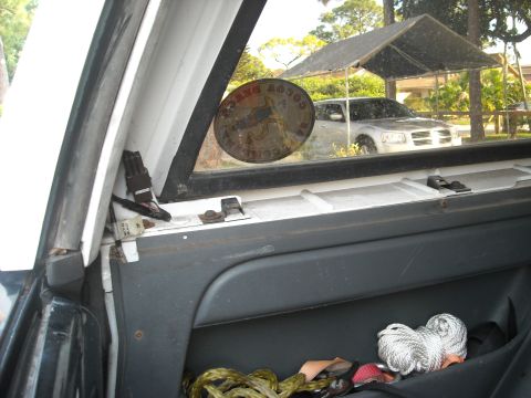 1994 Ford Bronco - A silver SUV is visible through the window of another vehicle, parked under a carport.