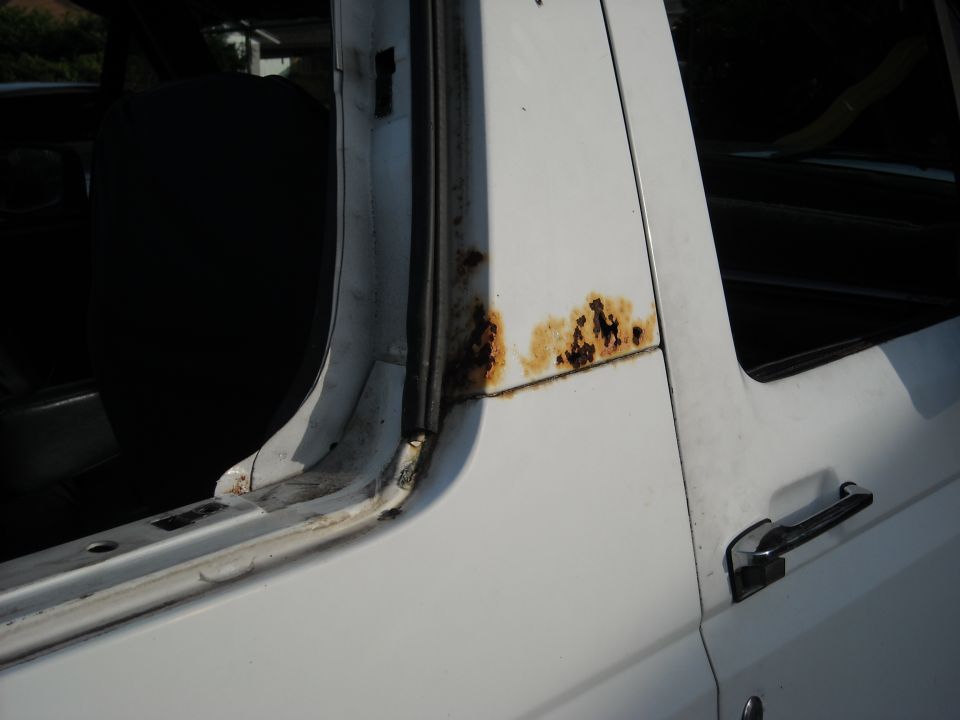 White pickup truck door frame showing rust around the window seal. Supermotors.net logo visible