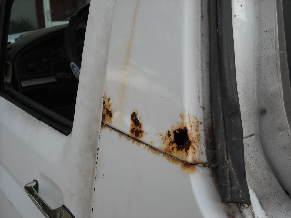 White vehicle door frame with significant rust damage