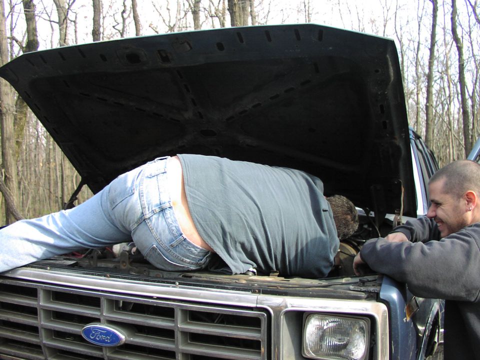 1986 Ford Bronco engine bay with person working on it
