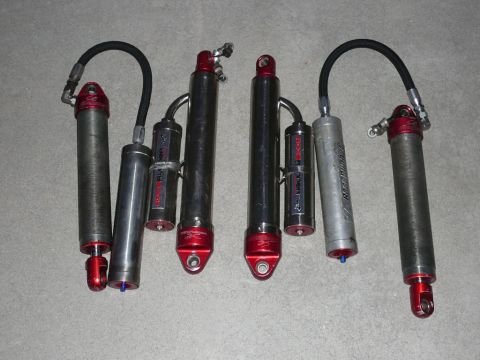 1988 Ford Bronco - A collection of four shock absorbers, some with visible branding, are laid out on a textured surface.