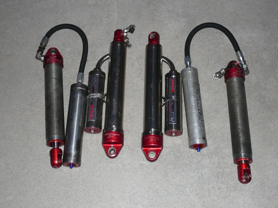 Four shock absorbers with red accents and black hoses