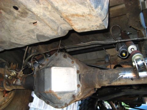 1989 Ford Bronco - Close-up view of the rear axle and suspension system of a vehicle, showing the differential and shock absorbers.