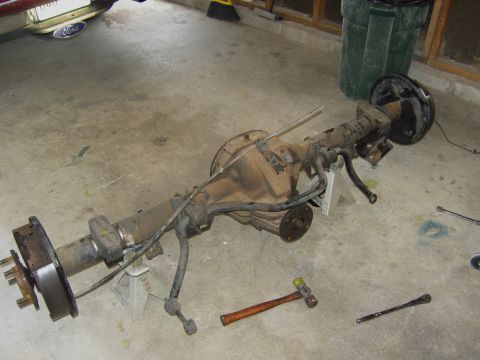 2007 Ford Mustang - A disassembled rear axle assembly rests on jack stands in a garage, with tools nearby.