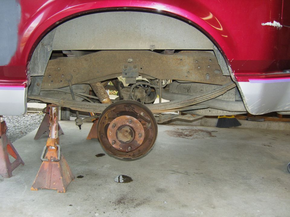 Rear axle assembly with leaf springs and brake drum removed, vehicle supported by jack stands