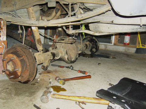 2007 Ford Mustang - Close-up of a vehicle's rear axle assembly and suspension components, with tools scattered around.