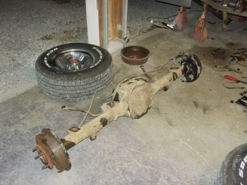 2007 Ford Mustang - Disassembled rear axle assembly and spare tire are on the garage floor.