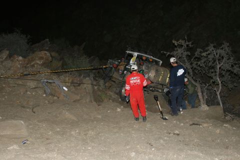 1996 Ford Bronco - Rescue workers attempt to pull a stuck off-road vehicle from a difficult terrain at night.