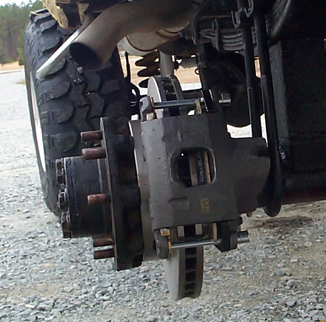 Disc brake caliper, vented rotor and 8-lug hub on a lifted truck axle with wheel removed