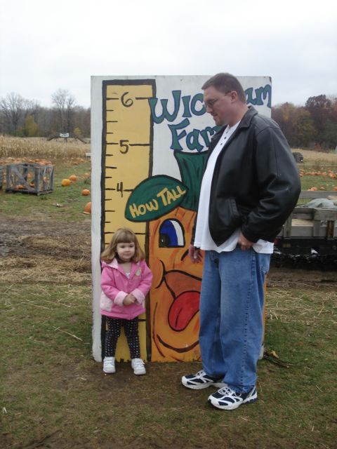 2000 Ford Crown Victoria - A man and a young girl stand next to a painted pumpkin height chart at a farm, likely a pumpkin patch.