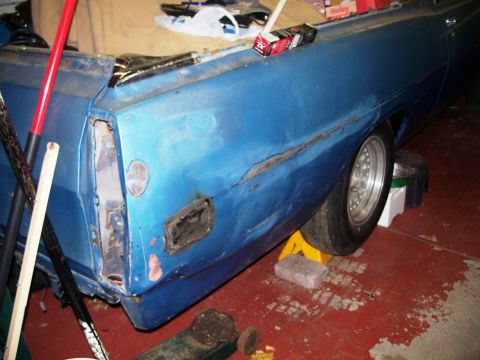 1971 Ford Ranchero - The rear of a blue vehicle displays significant body damage and rust, indicating repair work.
