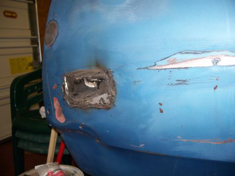 1971 Ford Ranchero - Close-up of a blue vehicle body panel with areas of rust and filler, indicating repair work in progress.