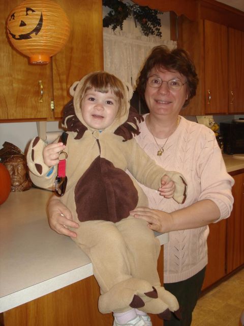 2000 Ford Crown Victoria - A woman holds a child dressed as a lion in front of kitchen cabinets, with a jack-o'-lantern decoration visible.