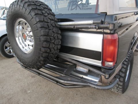 1986 Ford Bronco - Modified Ford Bronco rear with spare tire and custom bumper. The rear window has 'TBR Baja Racers' decals.